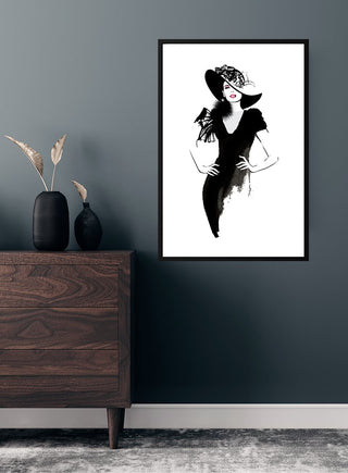 Art print of a woman in a black dress and hat, minimalist style, displayed on a dark wall above a wooden dresser.