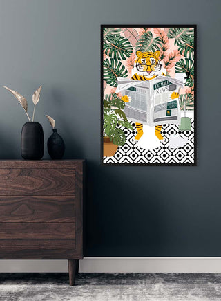 Framed art of a tiger reading Tiger News, surrounded by plants, hanging on a dark gray wall above a wooden dresser.
