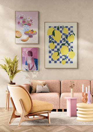Framed artwork of bright yellow lemons on a checkered background hangs above a modern pastel sofa in a stylish room.