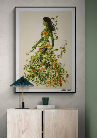 Framed artwork of a woman in a dress made of green leaves and orange flowers, titled The Garden Muse by Elara Monet.