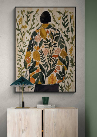 Framed "Whispers of Spring" by Elara Monet showing a figure in a floral coat, displayed above a modern cabinet.